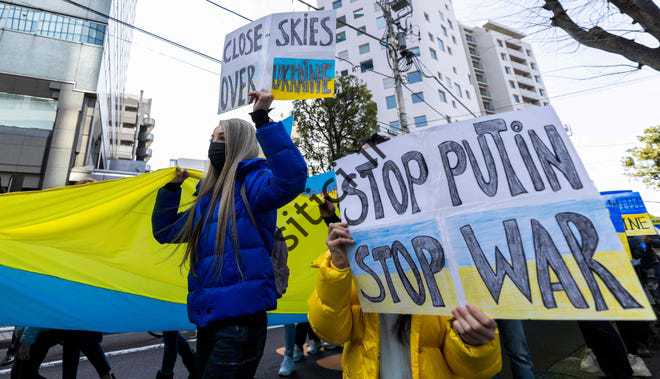 معترضان در اعتراض به اقدامات روسیه در اوکراین در جریان تظاهراتی در توکیو، پلاکاردهایی در دست دارند.